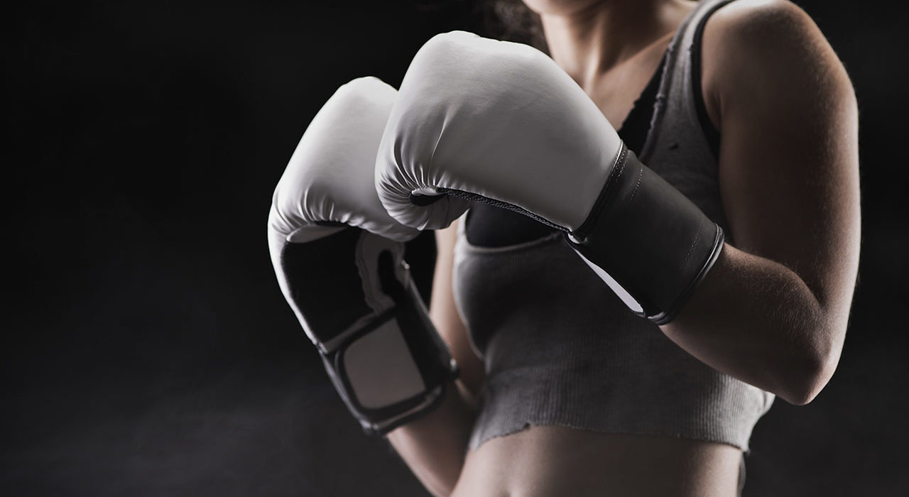 A woman wearing boxing gloves in the dark.