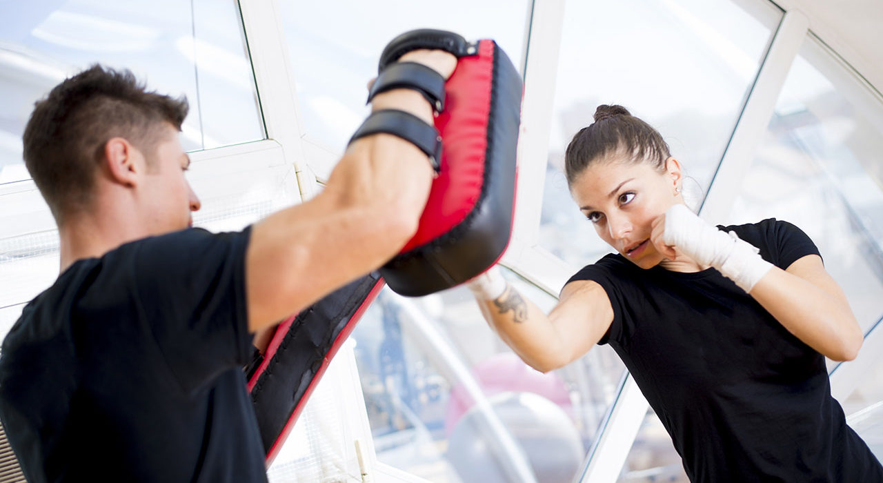 A man and woman are practicing boxing in the gym.